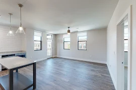 Open concept living room with wood-inspired flooring, access to the kitchen, and neutral colored walls