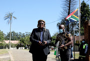 The SA flag is flown half mast at King Goodwill Zwelithini Zulu's KwaKhethomthandayo Royal Palace where hundreds of people have been making their way in and out to mourn the passing of the king. Pictured is the king's younger brother Prince Mbonisi Zulu outside the palace. 