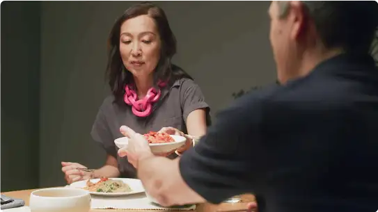 Lauryn hands a plate of kimchi to her husband during meal time.