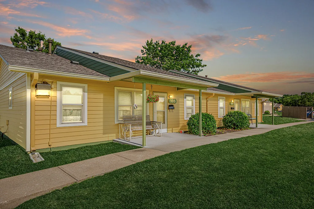 Lom Vista apartment building with yellow siding and green trim at dusk