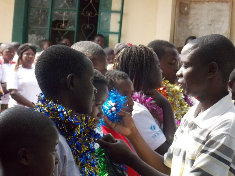 A father adjusts a garland on his daughter during graduation of an alternative rite of passage on November 12, 2017 at Ikerege in Kuria West