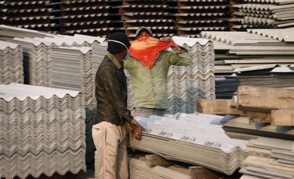 Workers in a factory handling asbestos without proper personal protective gear.