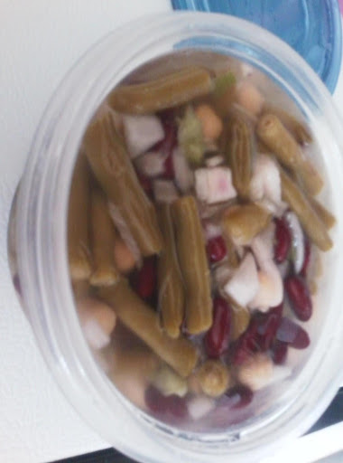 Green bean salad in a plastic container with a blue lid