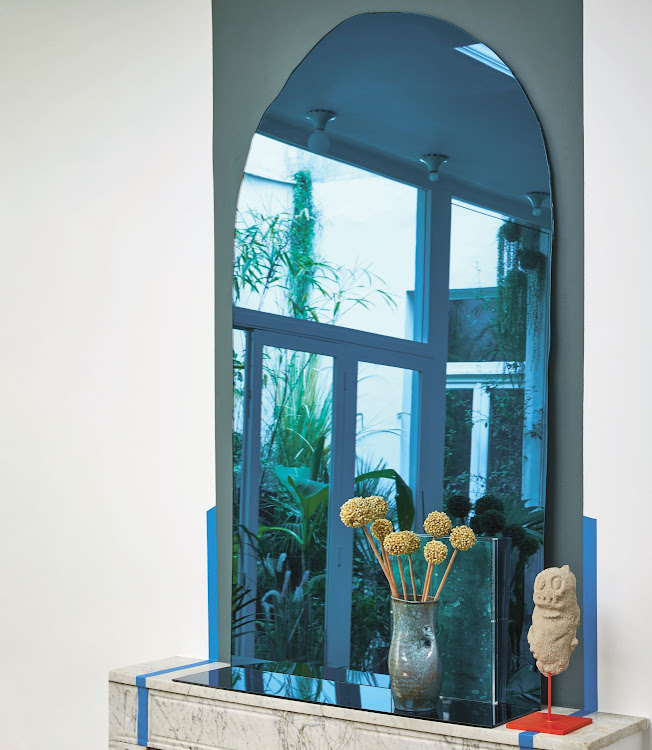 The commanding blue mirror propped up above the fireplace in the living room was designed by Aumas, its edges intentionally irregular, reflecting his leanings towards objects that are characterful and unique in their imperfections. The small sculpture is by French artist Olivier Millagou.