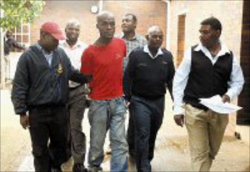ACCUSED; Paul Mofokeng, manacled, is led by policemen yesterday. He had been on the run for almost two months. Pic. Lucky Nxumalo. 22/01/08. © Sowetan.