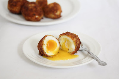 photo of a Fried Bacon Wrapped Egg sliced in half with yolk oozing out