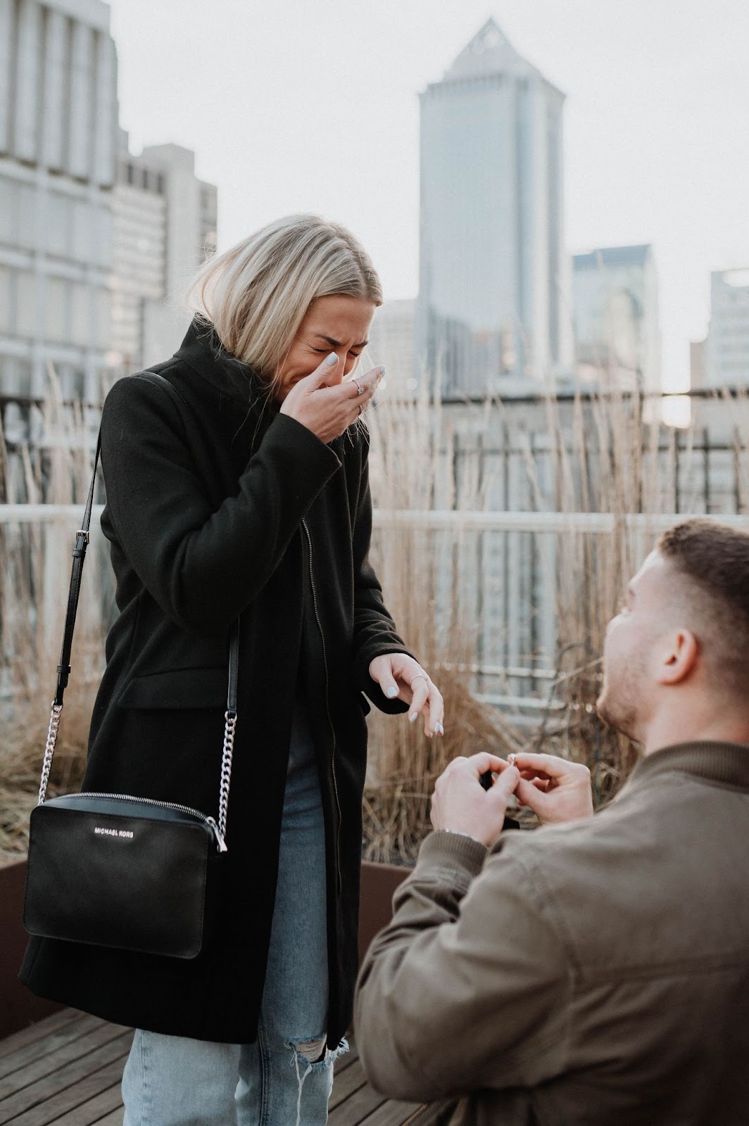 Woman crying as she notices man proposing to her.