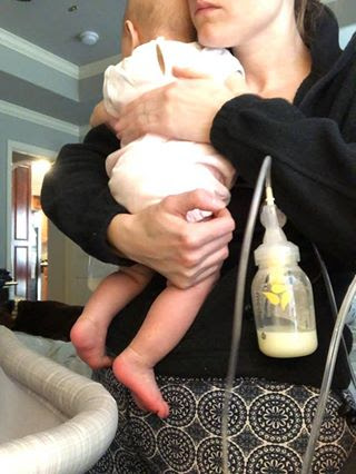 woman carrying baby while pumping brast milk with a hands-free pumping bra