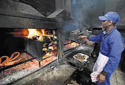 HOT STUFF: A staff member prepares meat for patrons at Mzoli's Place in Gugulethu, Cape Town.