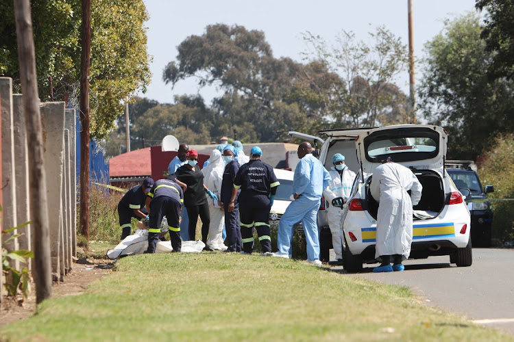 Members of the forensic pathology team with members of the police investigating the murder of two young boys found mutilated and murdered in Soweto. File image