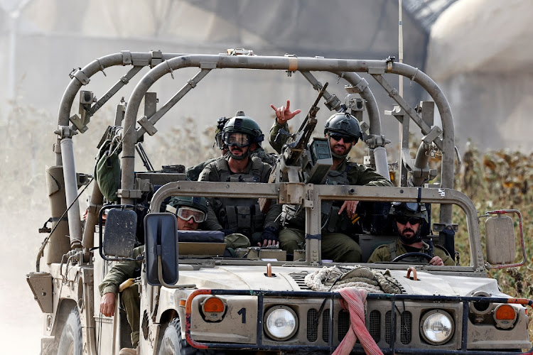 An Israeli soldier gestures while riding in a military vehicle, amid the ongoing conflict between Israel and the Palestinian Islamist group Hamas, near the border with Gaza, in southern Israel, December 9, 2023.