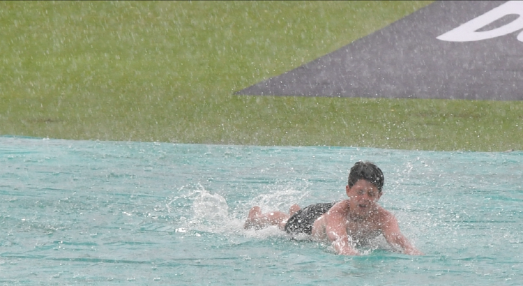 With play halted by rain at the end of day one of the first Test between South Africa and India at SuperSport Park in Centurion on Tuesday, a young fan makes a slip and slide of the wicket cover.