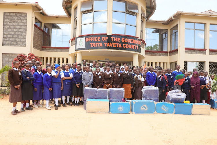 Beneficiaries of the Sh15 million Taita Taveta County Comprehensive Secondary School Scholarship Programme pose for a photo with Governor Andrew Mwadime and Deputy Governor Christine Kilalo outside the governor's office on Monday