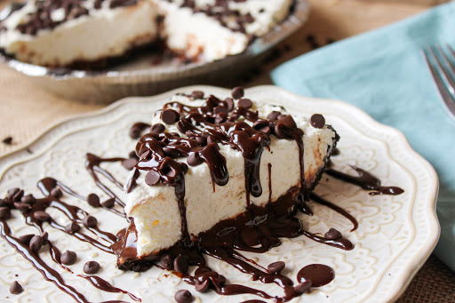 A slice of death by chocolate cheesecake with hot fudge drizzled on the plate.