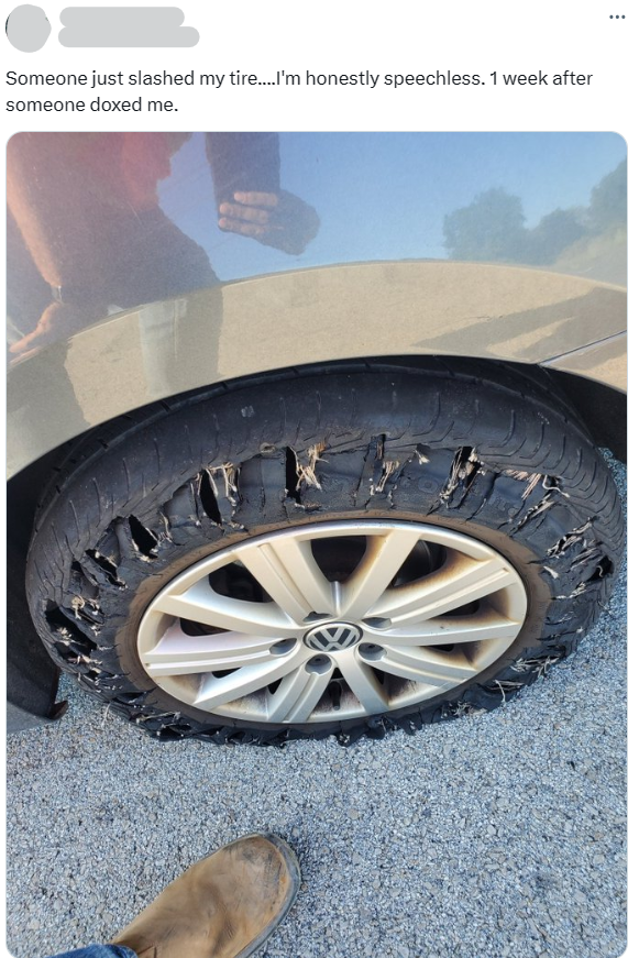 X (Twitter) post with a photo of slashed car tires after being doxxed