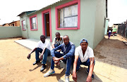 Parolees Mpho Dikgane, Thabo Mokoala, Richmond Tau and Kabelo Mhlongo sit outside a house that they helped rebuild after it was destroyed by fire.