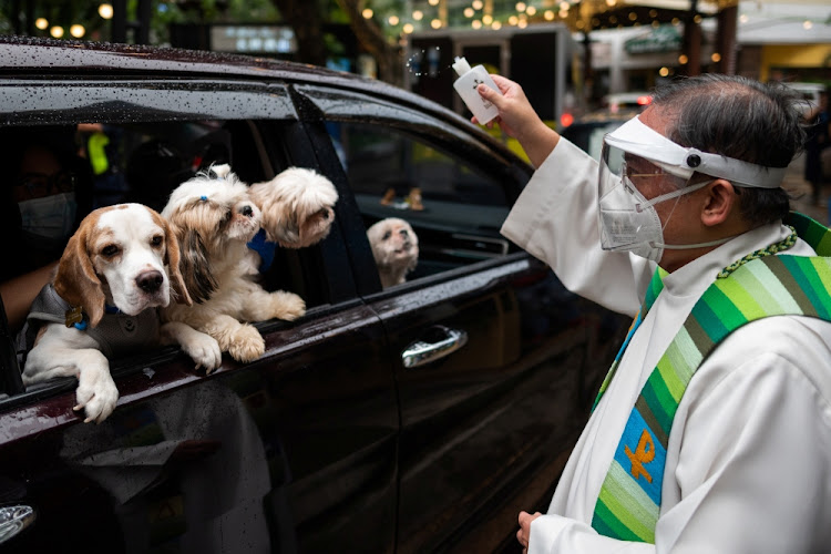 A priest sprinkles holy water on dogs at a drive-through pet blessing a day before World Animal Day, at Eastwood Mall, Quezon City, Metro Manila, Philippines on October 3 2021.