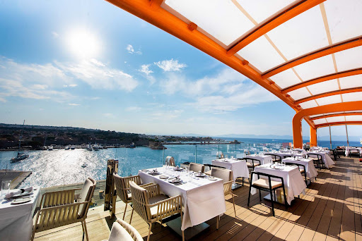 Dine or enjoy a drink while perched on the Magic Carpet platform, shown here on a Celebrity Edge class ship in Rhodes, Greece.