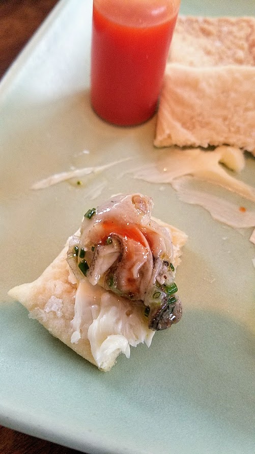 Lafitte's, a hidden bar located on the 2nd floor of The Waiting Room in NW Portland offering cocktails that are champagne and absinthe forward and a small bites menu that includes this dish, Cold Smoked Oyster with goat milk butter, saltines and hot sauce