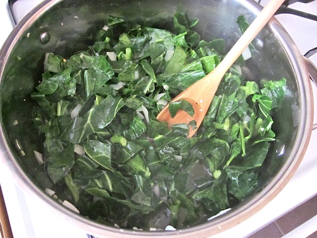 wilted collared greens in pot with wooden spoon 