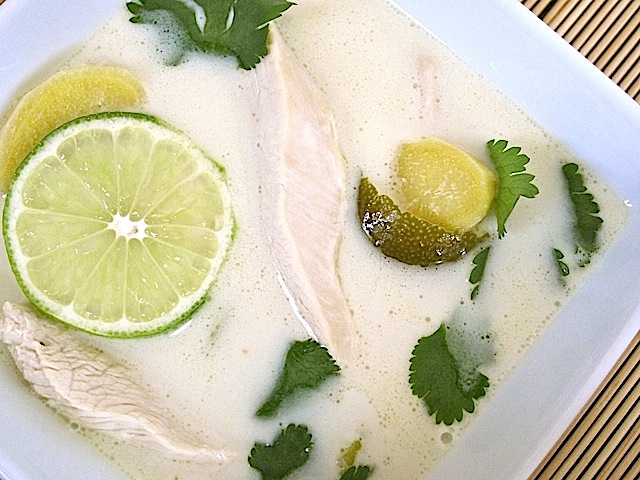 Close up of a square bowl full of Chicken Coconut Soup, garnished with lime and cilantro