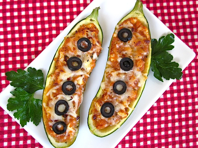 top view of two pizza stuffed zucchini with olives on top 