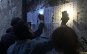 Voters use their cellphones to light as they look for their names on the voter's roll outside a polling station during the presidential election in Kinshasa, Democratic Republic of Congo, on December 30 2018. 
