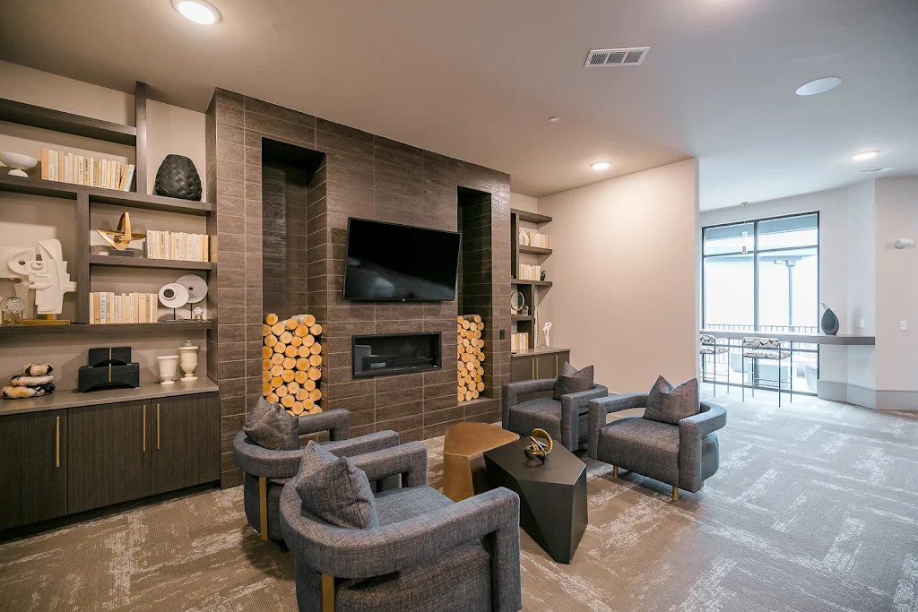 Upscale lounge seating area with a mounted TV, plush seating, and decorative shelving accents