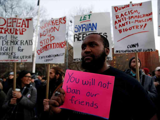 Isaiah Dupree holds a sign as demonstrators gather at Washington Square Park to protest against US President Donald Trump in New York, January 25, 2017. /REUTERS