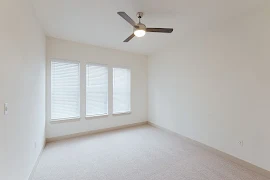 Bedroom with three windows with blinds, beige carpet, ceiling fan, and light walls