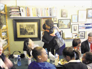 Obama embraces Karen Dudley, the owner of The Kitchen, while a member of her entourage looks on Pictures: DAVID MALLISON