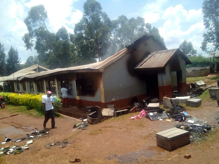 A man walks near some properties and a dormitory which were burnt in a fire at Ober Boys High School on August 29, 2022.