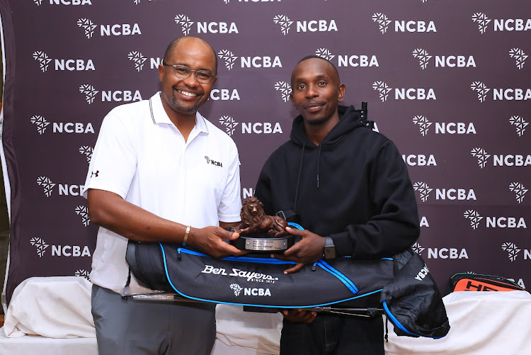 Kitale Golf Club's Kevin Nyaga (R) receives his Division One winner's trophy from NCBA's Group director for Retail Banking, Tirus Mwithiga.