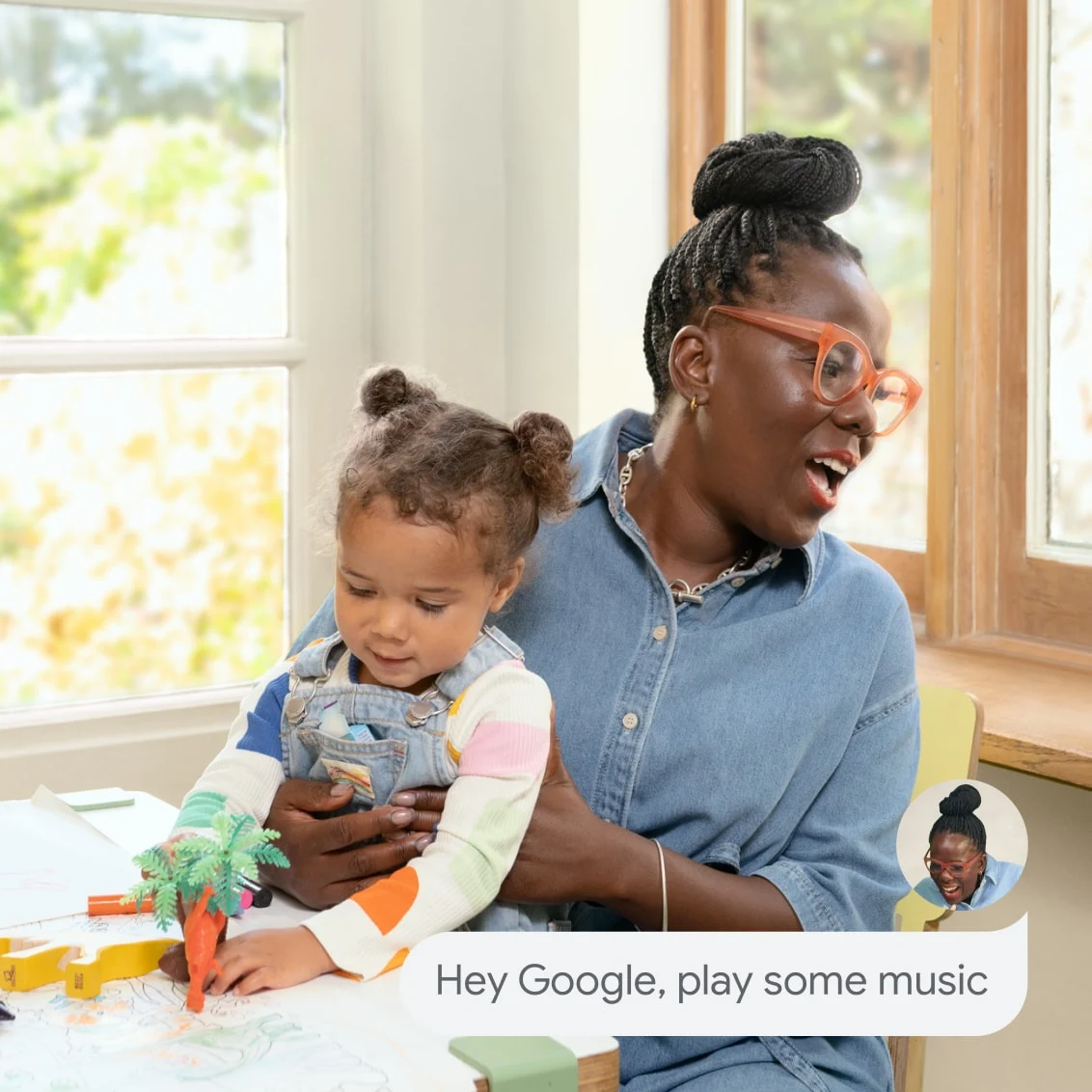 A parent holds their child and says 'Hey Google, play some music' without interrupting playtime.