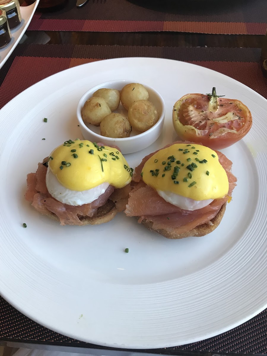 Eggs Benedict with smoked salmon roasted tomato and potatoes