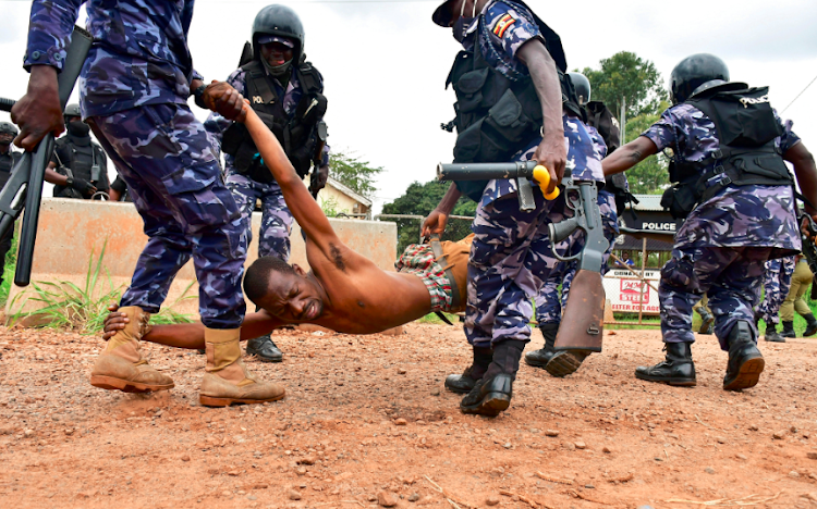 Ugandan riot policemen detain a supporter of presidential candidate Robert Kyagulanyi, also known as Bobi Wine, in Luuka district, eastern Uganda on November 18 2020.