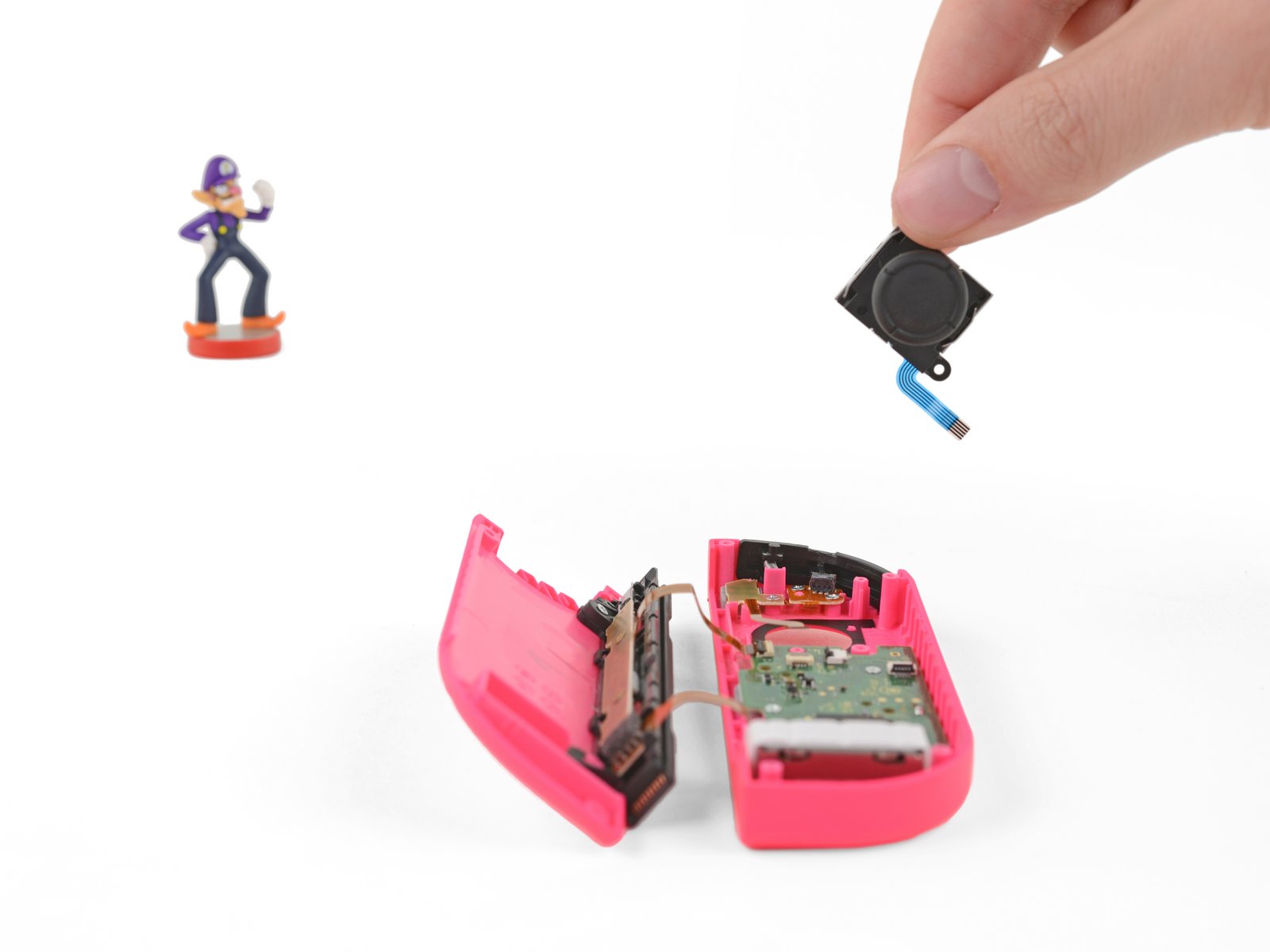 Switch Joy-Con joystick replacement with Waluigi figurine in the background