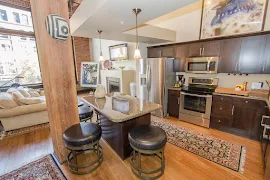 Kitchen with wood cabinets, stainless steel appliances, island, stone countertops, pendant lights