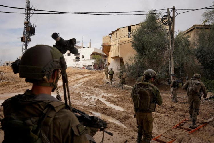 Israeli soldiers walk during their ground operation against Palestinian Islamist group Hamas at a location given as Khan Younis, Gaza Strip in this handout image released December 24, 2023. Israel Defense Forces/Handout via REUTERS THIS IMAGE HAS BEEN SUPPLIED BY A THIRD PARTY