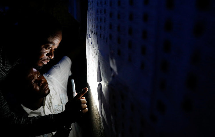 Voters use a phone to search for their names on the Independent National Electoral Commission list, at the Mavuno polling centre, to cast their votes.