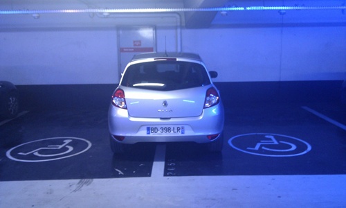 photo of a luxury car taking-up two handicap parking space