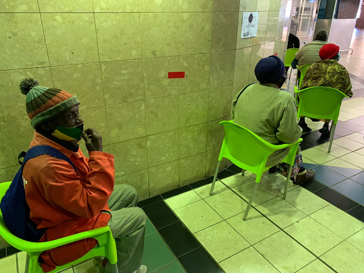 Solomon Laka, 72, sits in a queue at the FF Ribeiro Clinic, waiting to be vaccinated.