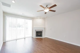 Living room with wood-inspired flooring, fireplace, sliding glass door, and ceiling fan