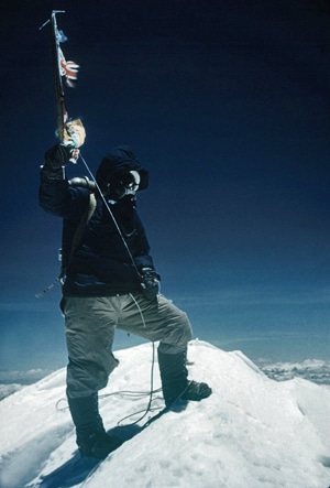 A man standing on the peak of snow mountain and holding snow Axe.