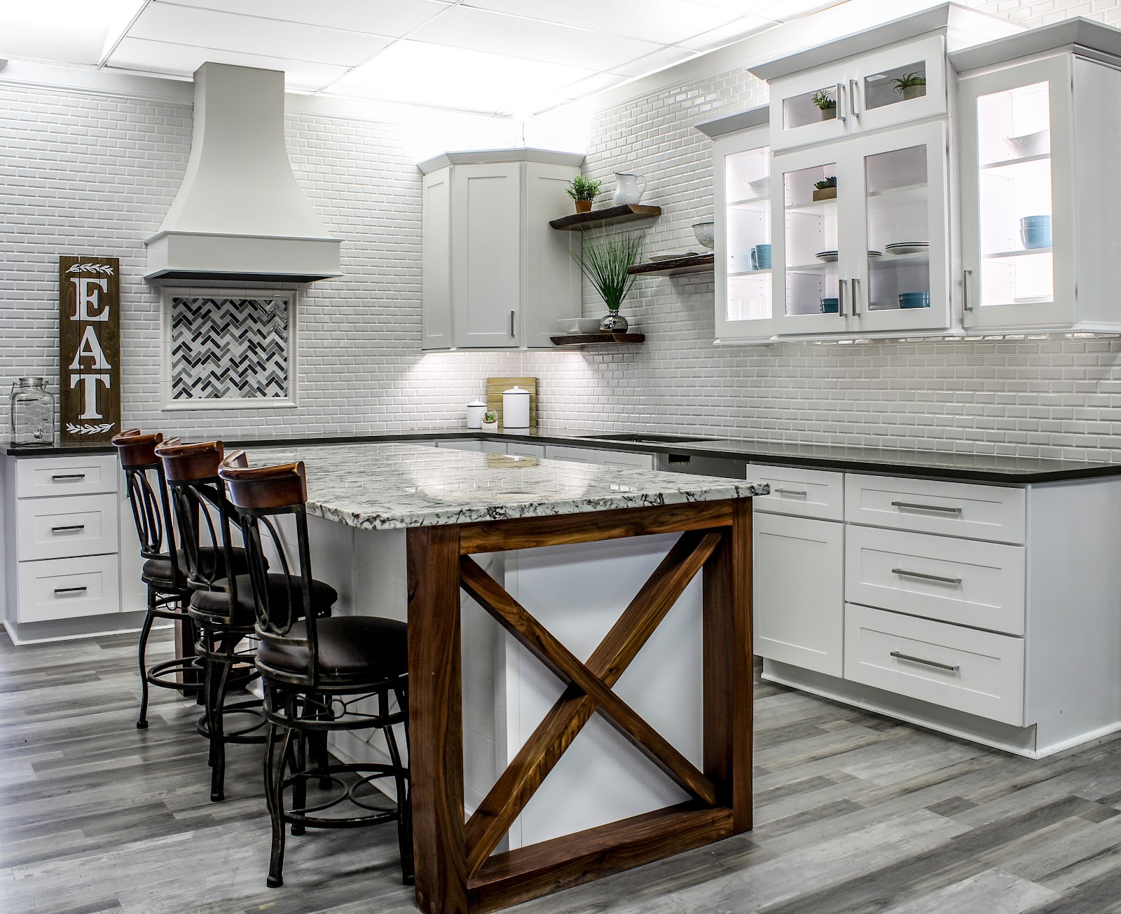 showroom featuring grey flooring, white shaker cabinets and granite countertops with black and white coloring