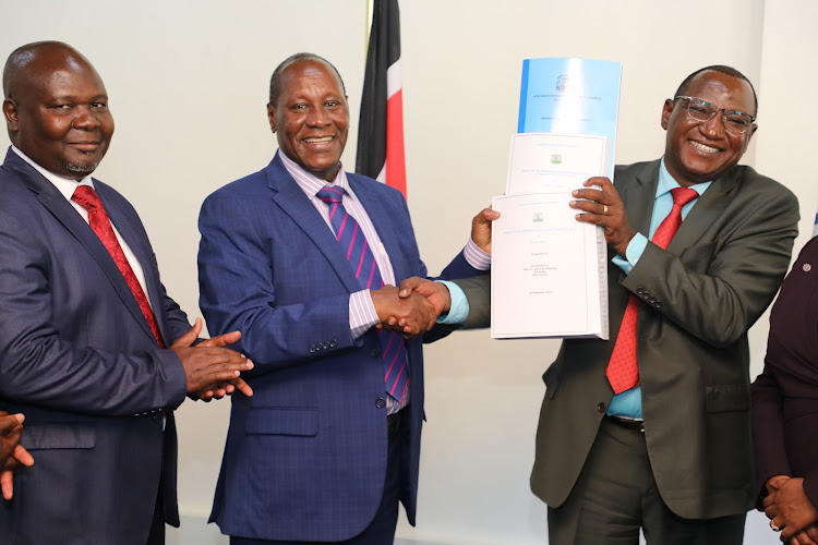 Kitui Governor Julius Malombe receives pending bills review committee report from chairperson Nicholas Muthui as Deputy Governor Augustine Kanani looks on.