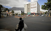 A man walks past a building in Cape Town covered with a poster aimed at limiting the  spread of Covid-19. 