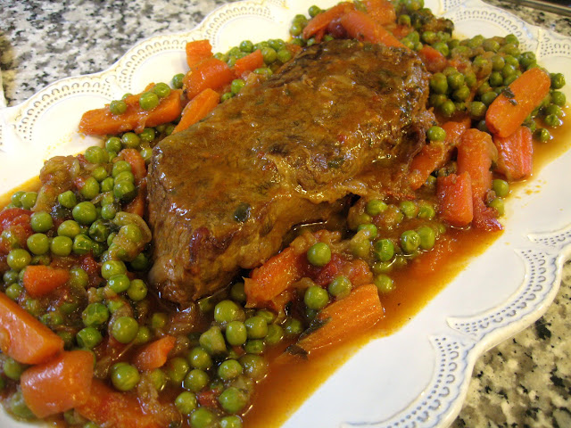 Italian pot roast ready to be served - with peas and carrots.