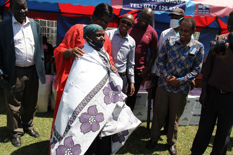 Homa Bay Woman Representative Gladys Wanga, Rivatex general manager Patrick Nyaga dress Rose Awino in a lesso made at Rivatex, at Pala market in Karachuonyo constituency on October 2, 2020