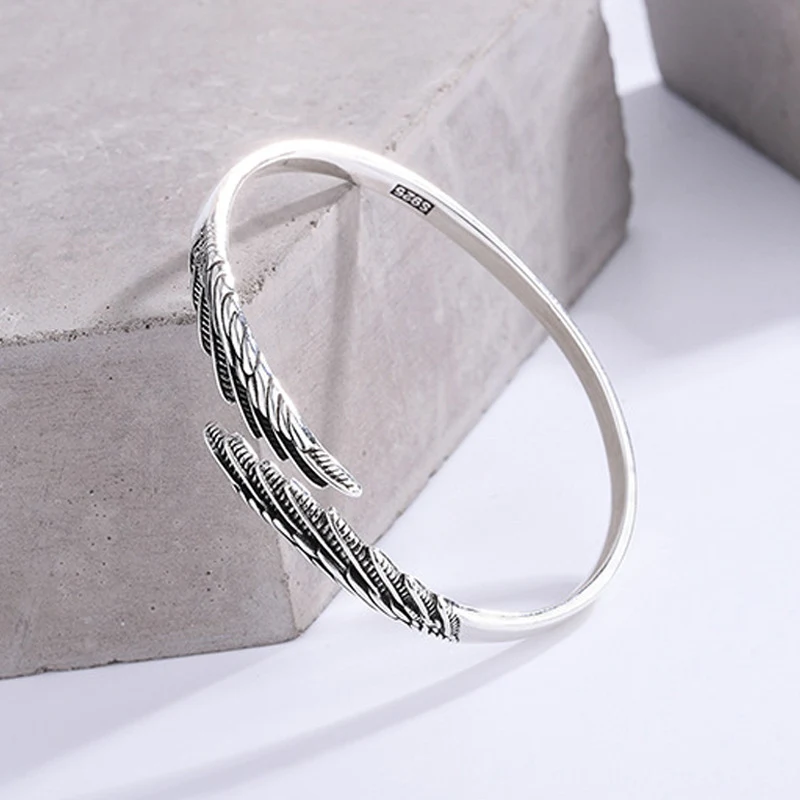 Zilver vergulde oude engelen vleugels armband, veren design, elegant sieraad, symbolisch voor bescherming en stijl.